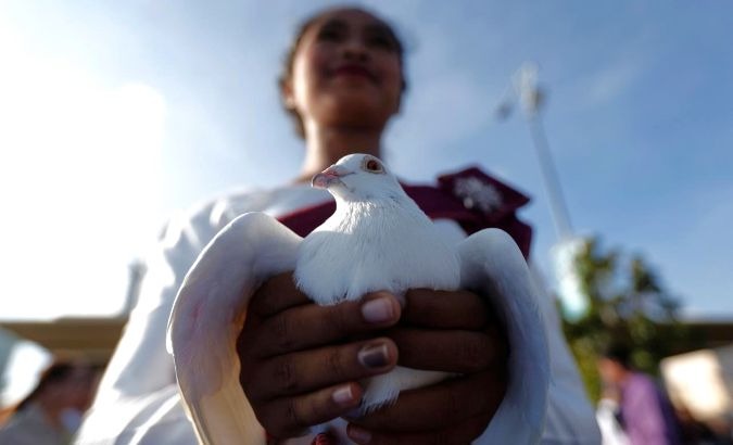 A girls holds a pigeon during a ceremony to mark the 39th anniversary of the toppling of Pol Pot's Khmer Rouge regime, in Phnom Penh, Cambodia.