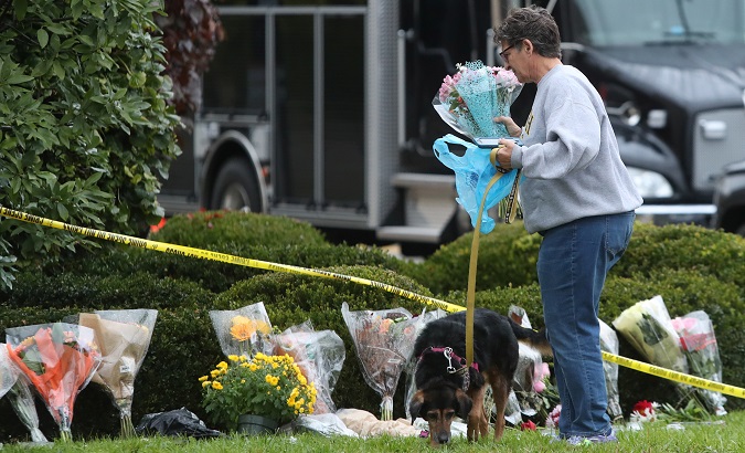 A woman brings flowers to an impromptu memorial at the Tree of Life synagogue following Saturday's shooting at the synagogue in Pittsburgh Pennsylvania.