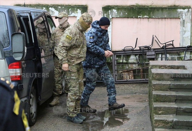 A member of Russia's FSB security service escorts a detained Ukrainian navy sailor (R) before a court hearing in Simferopol, Crimea Nov. 27, 2018.