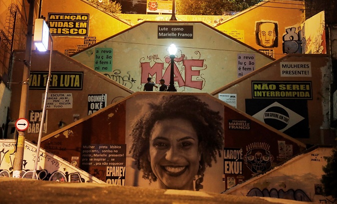 Men talk next to an image in tribute to late human rights activist and council woman Marielle Franco - who was assassinated in a shooting - nine months after her death, on Human Rights Day in Sao Paulo, Brazil, December 10, 2018.