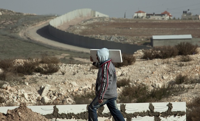 A Palestinian worker carries a stone for a wall being built in East Jerusalem.