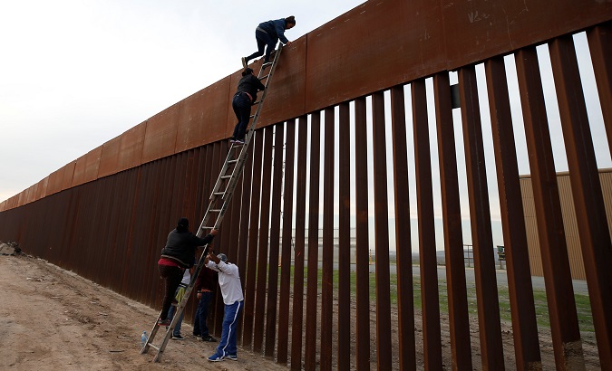 Honduran migrants climb a border fence to cross to the U.S. in Tijuana, Mexico, Dec. 21, 2018.