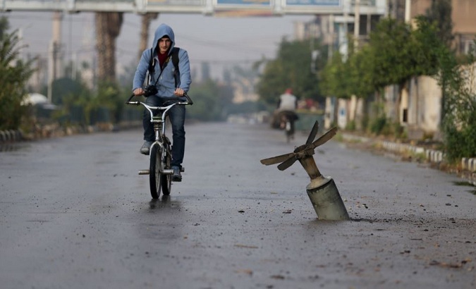 A resident rides his bicycle near what activists say is an exploded cluster-bomb shell in the Syrian town of Douma in November.