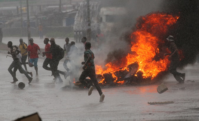 People run at a protest as barricades burn during rainfall in Harare, Zimbabwe Jan. 14, 2019.
