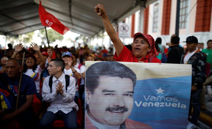 A supporter of Venezuela's President Nicolas Maduro holds a banner depicting him as he takes part in a gathering outside the Miraflores Palace in Caracas, Venezuela.