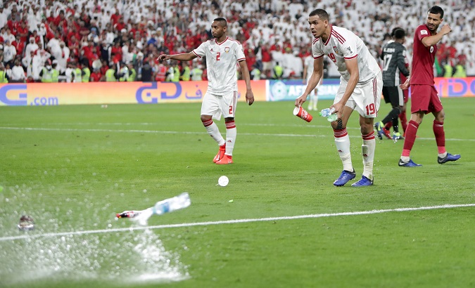 Ismail Ahmed of United Arab Emirates clears the pitch of object thrown by fans after Qatar's Hasan Al Haydos scored their third goal.