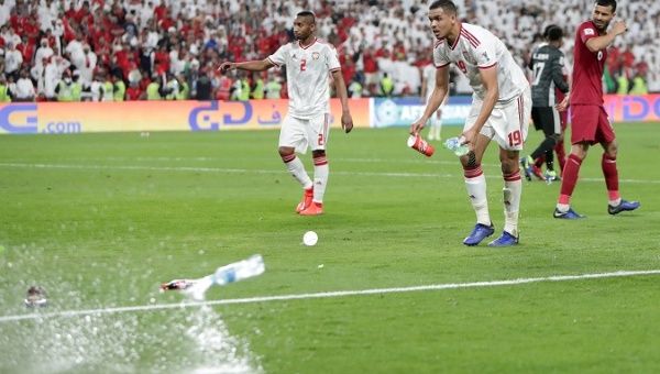 Ismail Ahmed of United Arab Emirates clears the pitch of object thrown by fans after Qatar's Hasan Al Haydos scored their third goal.