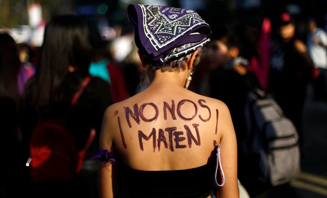 A woman protests against femicide and violence against women. The words on her back read 