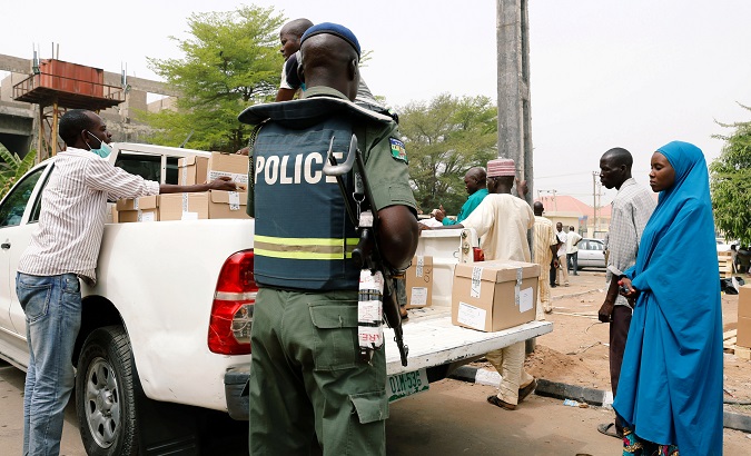 A police member oversees Ad-hoc staff loading boxes onto a truck during the distribution of election materials at the INEC office in Yola, in Adamawa State.