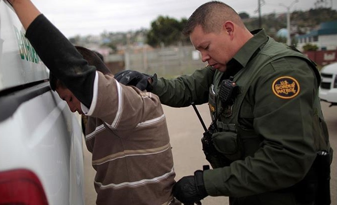 A United States border patrol agent pats down a man caught crossing from Mexico to the US .