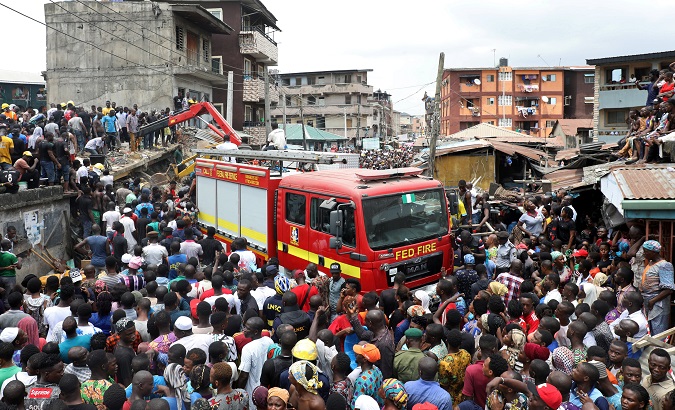 People gather as rescue workers search for survivors at the site of a collapsed building containing a school in Nigeria's commercial capital of Lagos, Nigeria March 13, 2019.