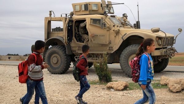 Syrian schoolchildren walk as U.S. troops patrol in Hasakah, Syria, Nov. 4, 2018.