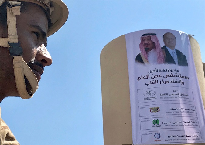 Yemeni soldier stands near a poster portraying Saudi Arabia's King Salman bin Abdulaziz Al Saud and Yemen's President Abdrabbuh Mansur Hadi outside a hospital renovated by Saudi Arabia in Aden