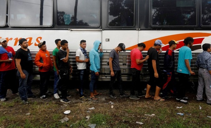 Honduran migrants, part of a caravan trying to reach the U.S., board a bus after a police check during a new leg of their travel in Rio Bravo, Guatemala.