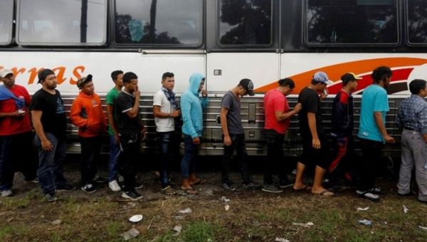 Honduran migrants, part of a caravan trying to reach the U.S., board a bus after a police check during a new leg of their travel in Rio Bravo, Guatemala.