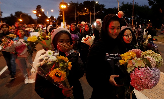 People reacts as they move flowers after police removed a police line, outside Masjid Al Noor in Christchurch