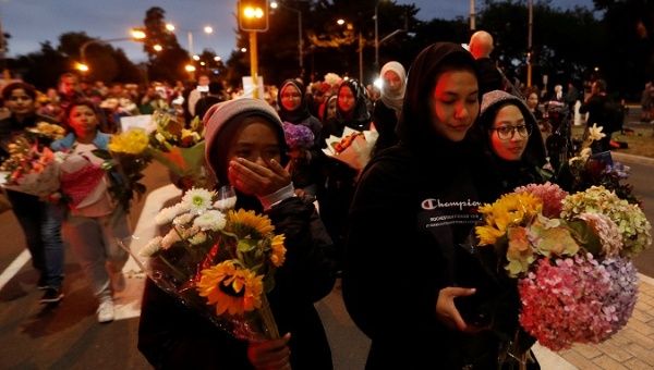 People reacts as they move flowers after police removed a police line, outside Masjid Al Noor in Christchurch