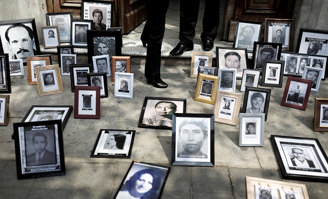 Pictures of missing people, placed by activists on the floor, are seen during a protest against a bill that would grant amnesty to war crimes committed during country's 36 year civil war outside the Congress, in Guatemala City, Guatemala March 13, 2019.