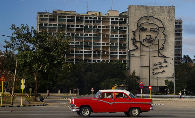 A vintage U.S.-made car passes beneath a mural of Che Guevara in Revolution Square in Havana, Cuba.