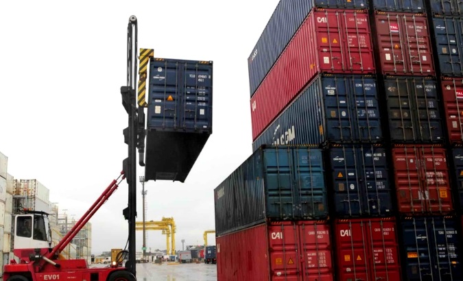 Workers load containers onto trucks from a cargo ship at a port in Jaragua do Sul, Santa Catarina state, Brazil