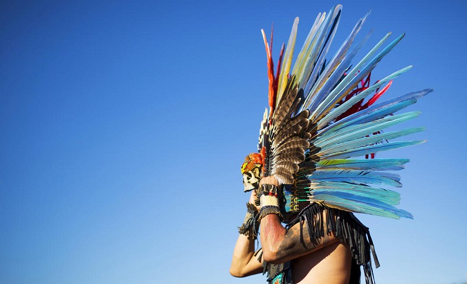 A Native American man dawns a traditional headdress in anticipation of an Indigenous Peoples' Day celebration.