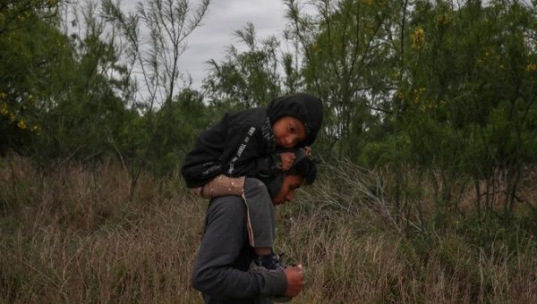 Ostavio, 5, from Guatemala, rests on the shoulders of his brother Eduardo as they walk through a field in hopes of finding refuge in the United States.