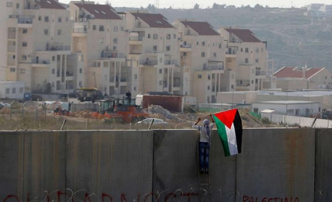 A man places the Palestinian flag on the Israeli separation wall dividing the main city from the settlements beyond.