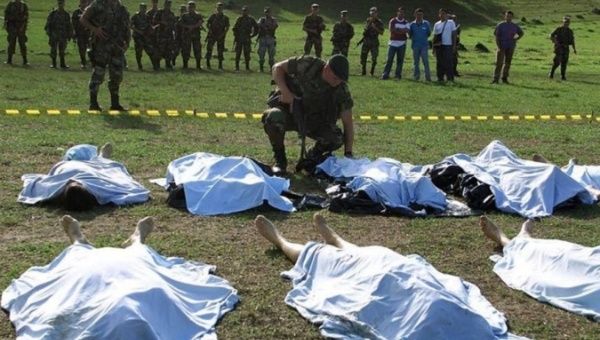 A Colombian soldier looks at the bodies of FARC rebels killed in combat in La Plata, Huila province, July 12, 2002