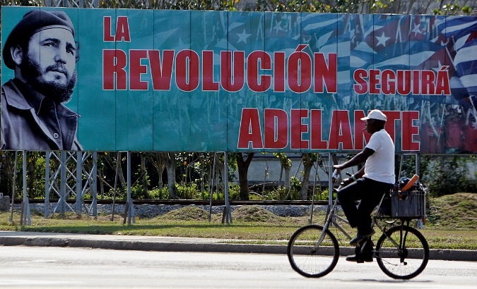 A man cycles past a sign touting the Cuban Revolution on Dec. 27, 2018, in Havana.