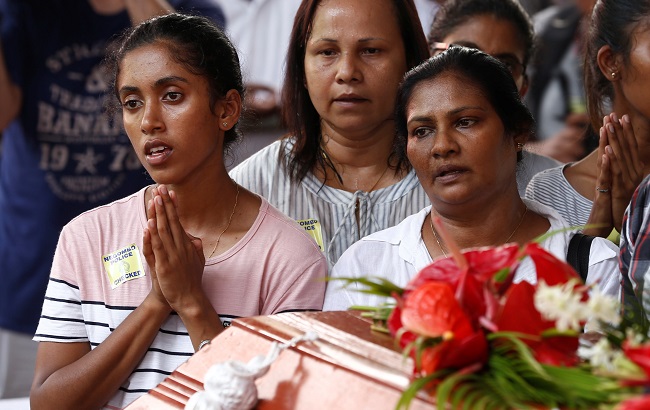 People attend a mass burial of victims at a cemetery near St. Sebastian Church in Negombo