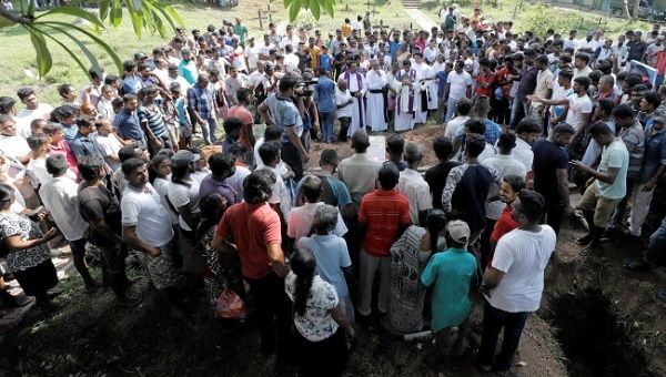 People attend a mass burial of victims, two days after a string of suicide bomb attacks on churches and luxury hotels across the island on Easter Sunday, in Colombo