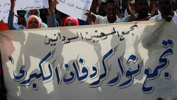 Sudanese protesters hold banners as they march through the defence ministry compound in Khartoum