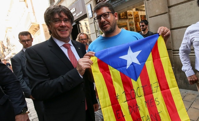 Catalonia's former President Carles Puigdemont poses next to a pro-independence supporter with a Catalan Estelada flag.