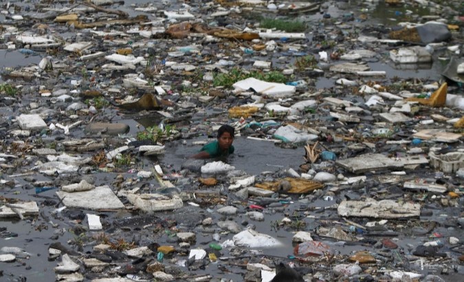 FILE PHOTO: A boy searches for fish in the polluted sea backwaters near marina beach in the southern Indian city of Chennai July 3, 2013. REUTERS/Babu/File Photo