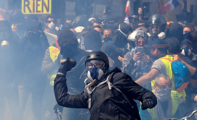 Tear gas floats around masked protesters during clashes before the start of the traditional May Day labour union march in Paris, France, May 1, 2019.