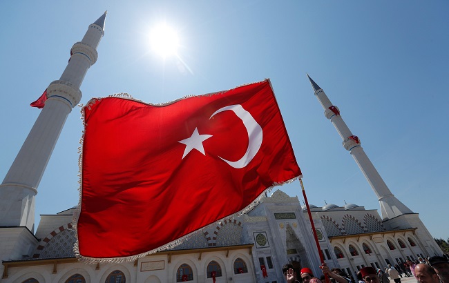 A man waves a Turkish flag at the courtyard of the Grand Camlica Mosque in Istanbul