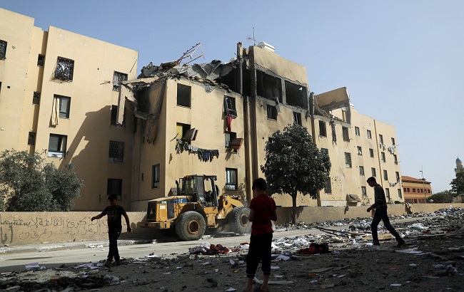 Palestinians are seen near an apartment block that was hit by an Israeli air strike, in the northern Gaza Strip