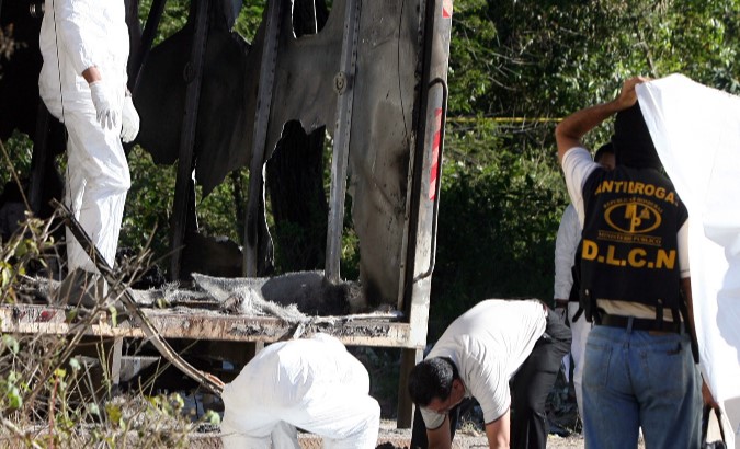 Honduran police lift one of the four burned bodies found inside a truck with Guatemalan license plates