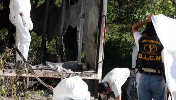 Honduran police lift one of the four burned bodies found inside a truck with Guatemalan license plates
