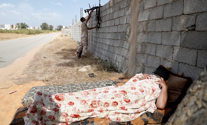 A Tripoli-based government soldier fires a rifle as other fighter takes a rest in Tripoli, Libya, May 12, 2019.