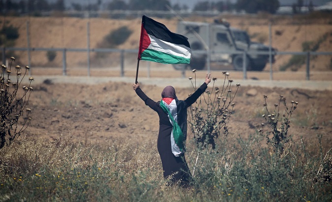 A man waves the Palestinian flag near the Israeli border fence in Gaza.