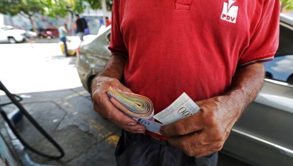 A worker holds a wad of Venezuelan bolivar notes at a state oil company PDVSA's gas station in Caracas, Venezuela May 17, 2019. 