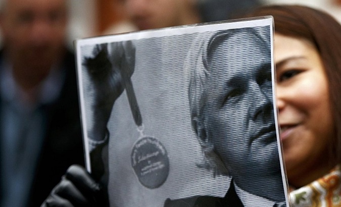 A supporter holding a photo of Julian Assange outside of the Belmarsh prison where he was recently confirmed to be in the medical ward.