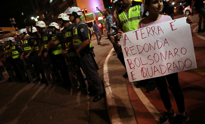 A girl holds a sign that reads, 'The Earth is Round, Bolsonaro is square' during a protest against cuts to federal spending on education in Sao Paulo, Brazil, May 30, 2019.