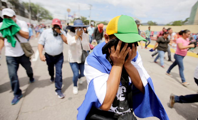 Demonstrators overcome by tear gas cover their faces during a protest against the government plans to privatize healthcare and education, in Tegucigalpa, Honduras May 30, 2019.