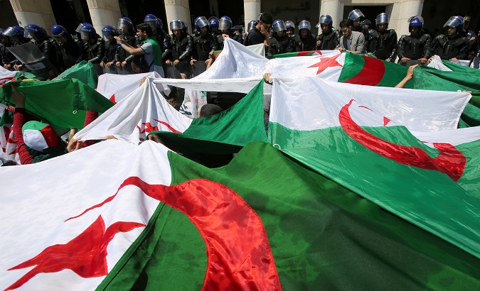 Police members stand guard as students carry national flags during an anti-government protest in Algiers, Algeria May 14, 2019.