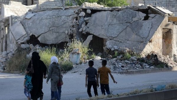 People walk near rubble of damaged buildings in the city of Idlib.