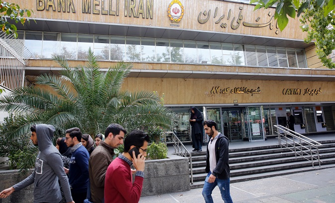 Iranians walk in front of a branch of the Bank Melli Iran in Tehran, Iran