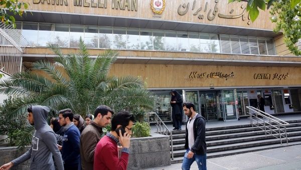 Iranians walk in front of a branch of the Bank Melli Iran in Tehran, Iran