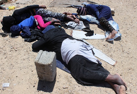 Migrants are seen lying on the ground after they were rescued by a coast guard patrol from a boat accident off the Libyan coast, in Qarabulli, east of Tripoli